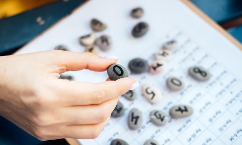 woman-numerologist-hand-with-pebble-stone-with-number-one-1 woman-numerologist-hand-with-pebble-stone-with-number-one-1